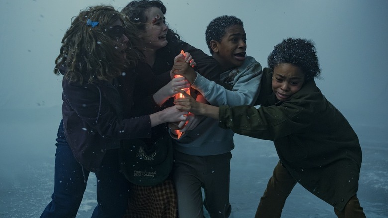 Marge, Ronnie, Lilly, and Will clutching a glowing artifact on It: Welcome to Derry