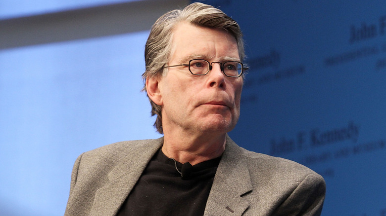 Stephen King with a grey suit jacket and black shirt