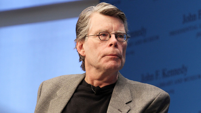 Stephen King with a grey suit jacket and black shirt
