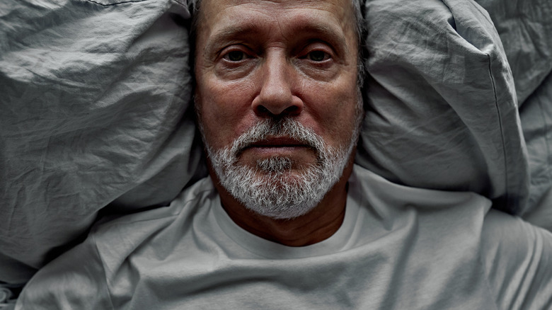 Old man lying on the bed with insomnia