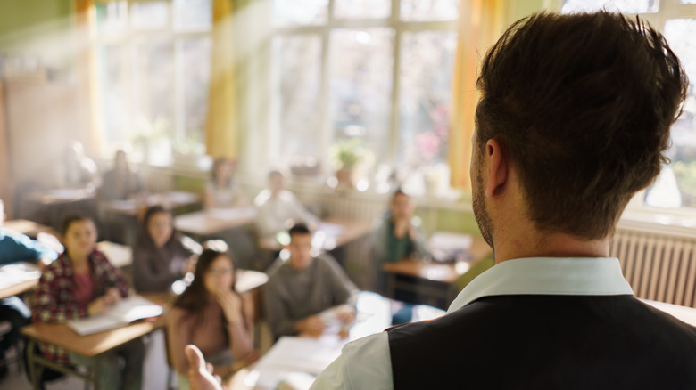 Rear view of a man facing students in a classroom