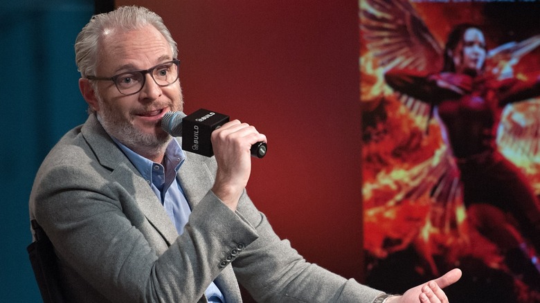 Francis Lawrence speaking into a mic in front of a poster for "The Hunger Games: Mockingjay Part 2" (2015)