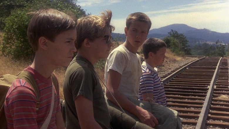 Wil Wheaton, Corey Feldman, River Phoenix, and Jerry O'Connell sitting on the train tracks in Stand By Me