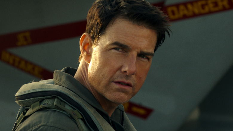 Maverick stands next to a plane in "Top Gun: Maverick" (2022)