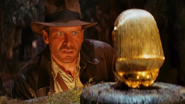 Indiana Jones inspecting a golden idol in "Raiders of the Lost Ark" (1981)
