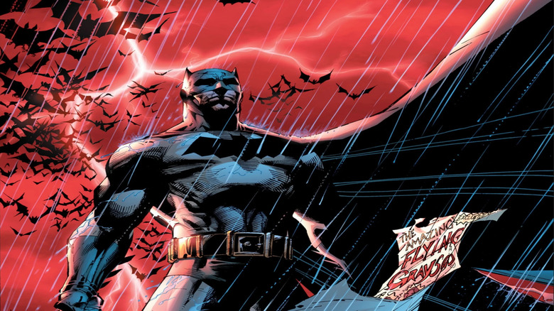 Batman standing against a red sky