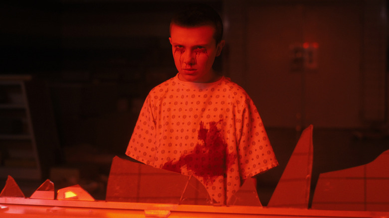 Eleven staring through shattered window