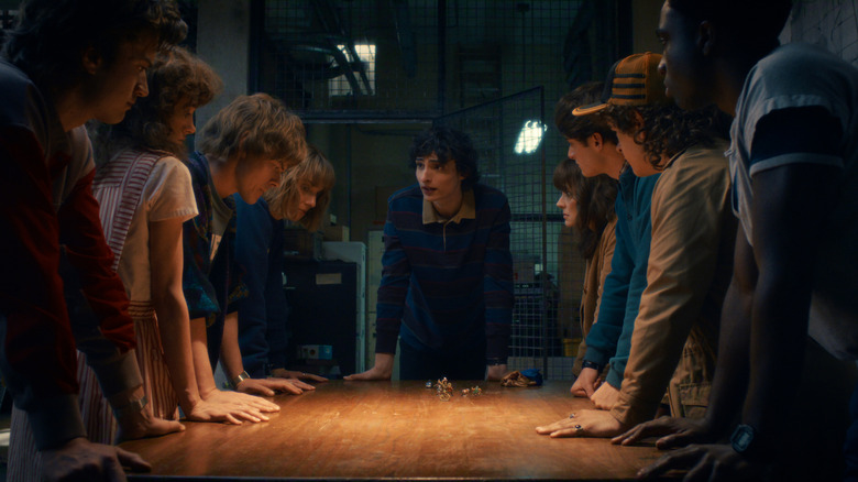 The whole gang gathered around a table led by Mike in Stranger Things 5
