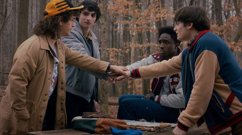 Dustin, Mike, Lucas, and Will putting hands together on Stranger Things Season 5