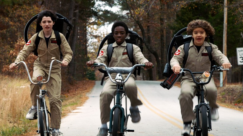 Finn Wolfhard, Caleb McLaughlin, and Gaten Matarazzo ride bikes in Ghostbusters costumes on Stranger Things