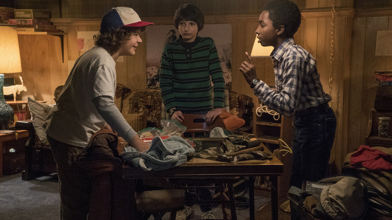 Dustin, Mike, and Lucas arguing over a table on Stranger Things