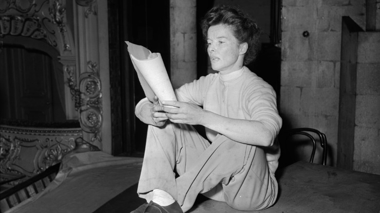 Katharine Hepburn sitting on a table and rehearsing lines
