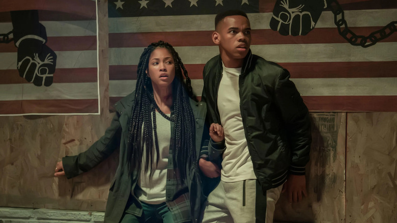 Nya and Isaiah leaning against a painted wall in "The First Purge."