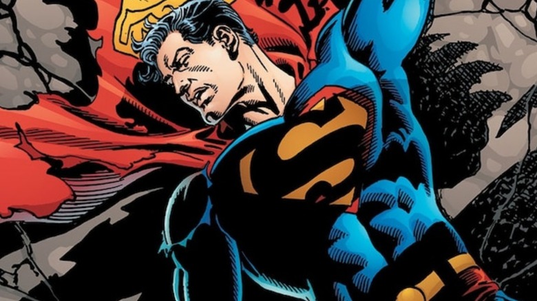 Superman lying in rubble with a tattered cape