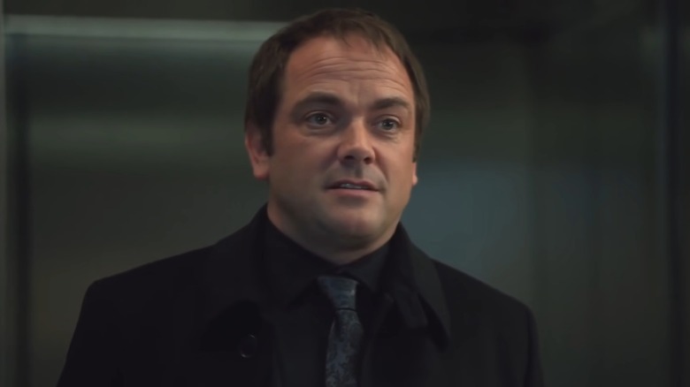 Crowley in a black suit and tie