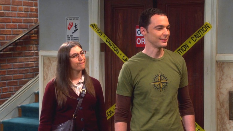 Amy and Sheldon smiling in hallway
