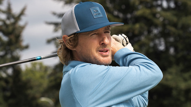 Pryce Cahill finishes a drive in a blue hat and shirt in 