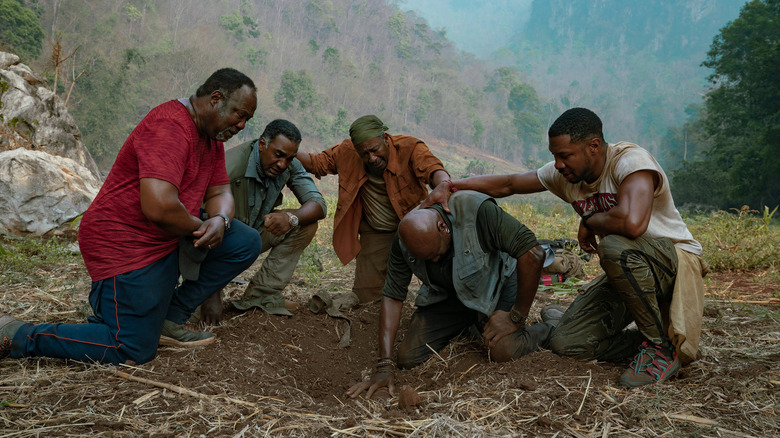 Five African American men taking a knee in the dirt in Da 5 Bloods (2020)