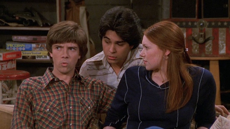 Eric putting his arm around Donna with Fez standing behind them in 