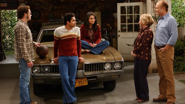 Jackie, Fez, and Hyde hanging around Eric's car as Red and Kitty look on in "That 70's Show"