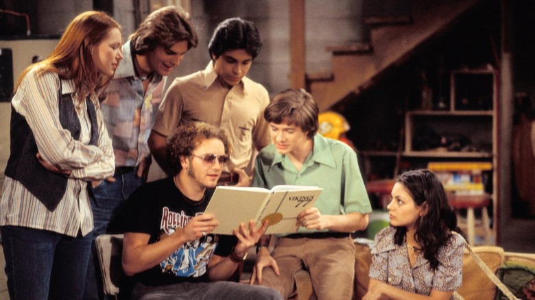The main cast of characters reading a yearbook in "That 70's Show"