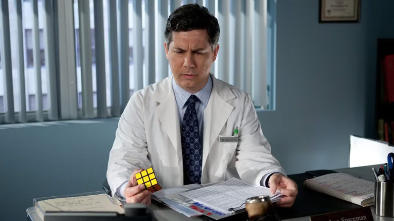 Dr. Spaceman at his desk inspecting a Rubik's cube on 30 Rock
