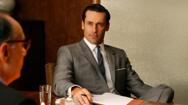 Don sitting at a conference table looking at someone in Mad Men