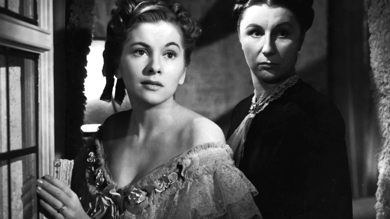The second Mrs. de Winter looking out of a window with Mrs. Danvers behind her in Rebecca