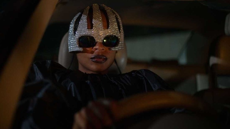 Shula driving in a costume in "On Becoming a Guinea Fowl" (2025)