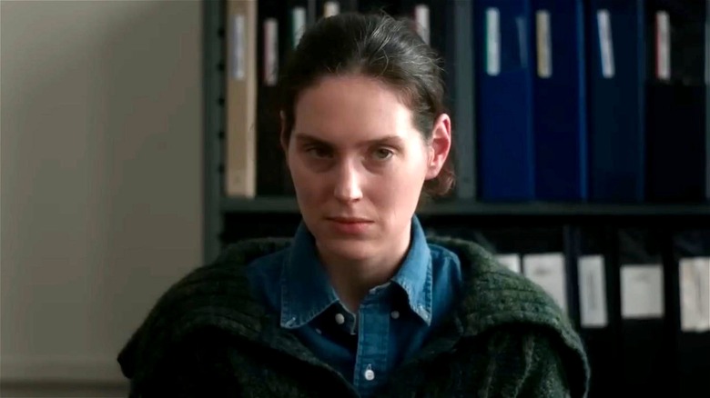 Agnes looks confused sitting by shelves of files in "Sorry Baby" (2025)