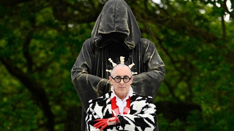 Alan Cumming in front of a statue in "The Traitors" (2023-present)