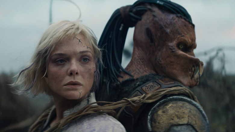 Thia strapped to Dek's back in Predator: Badlands