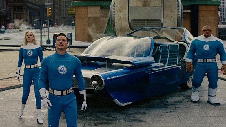 Sue Storm, Reed Richards, and Ben Grimm standing next to their car in "The Fantastic Four: First Steps"