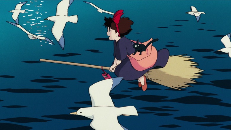 Kiki flies her broom over the ocean by seagulls, with Jiji on her bag, in "Kiki's Delivery Service" (1989)