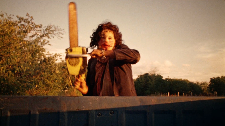 Leatherface wielding a chainsaw at a truck in The Texas Chain Saw Massacre (1974)