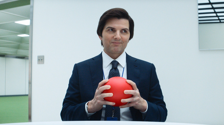 Mark S. holding a red ball and smirking on Severance