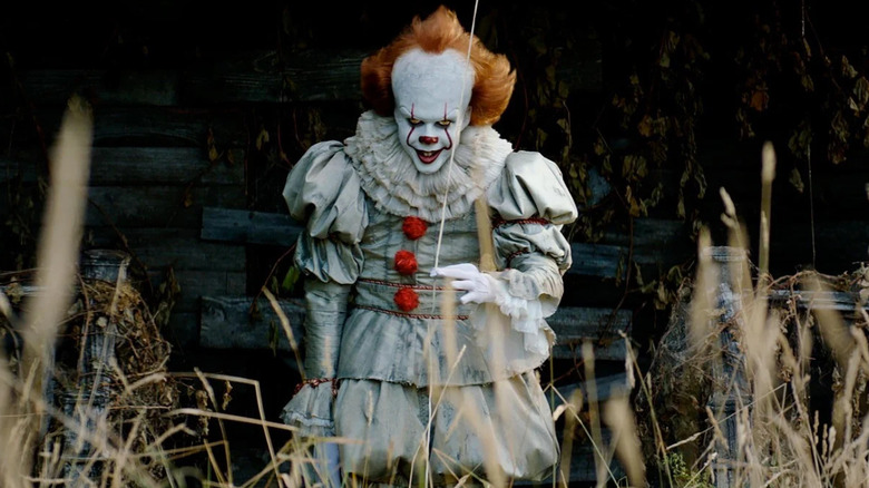Pennywise holding a balloon string and smiling