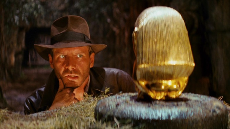 Indiana Jones admires a gold statue in an ancient temple in "Raiders of the Lost Ark" (1981)