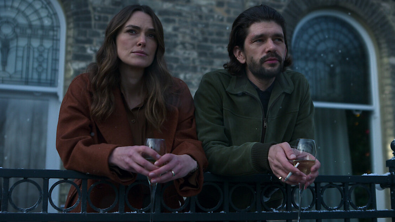 Helen and Sam leaning on a railing holding drinks in Black Doves (2024)