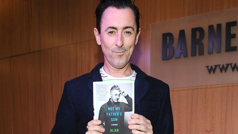Alan Cumming holding a book