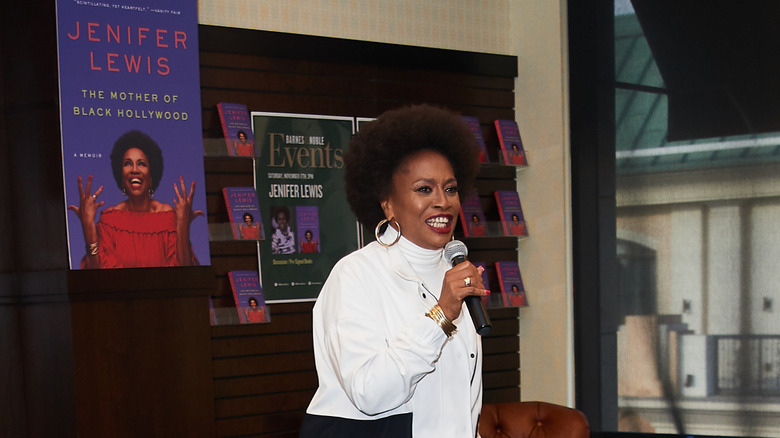 Jenifer Lewis with a microphone in front of a book display
