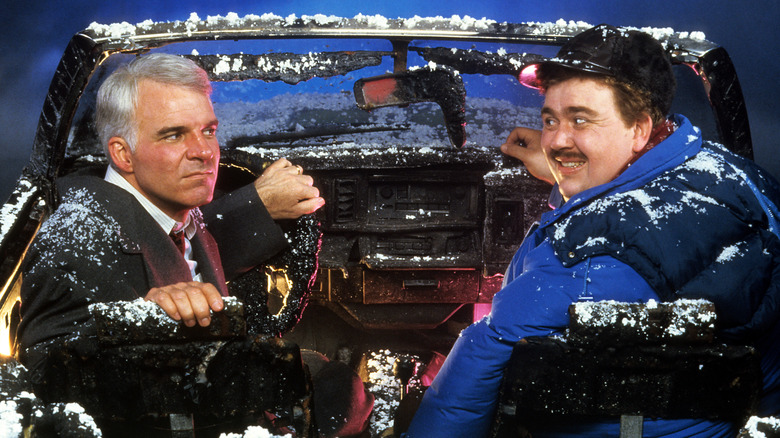 Neal Page and Del Griffith sit in a burned car in 'Planes, Trains, and Automobiles' (1987)