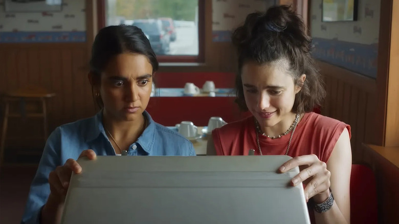 Jamie and Marion peer inside a briefcase in "Drive-Away Dolls" (2024)