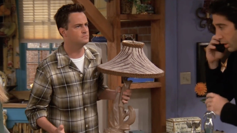 Chandler holds a lamp and looks at Ross quizzically on "Friends" (1994-2004)