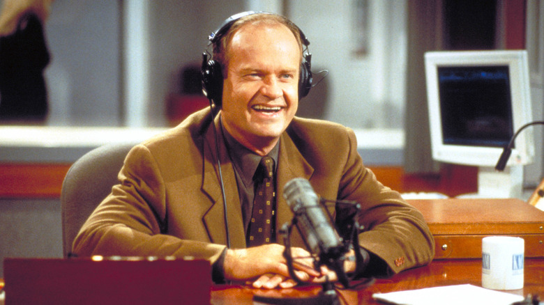 Kelsey Grammer as Frasier Crane sitting at a desk with headphones on