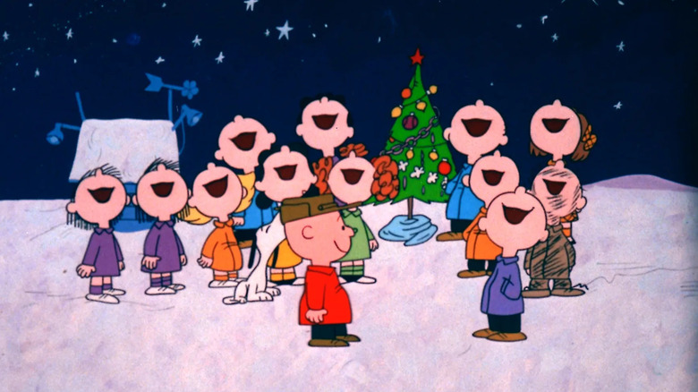 The cast of Peanuts singing outside around Christmas tree