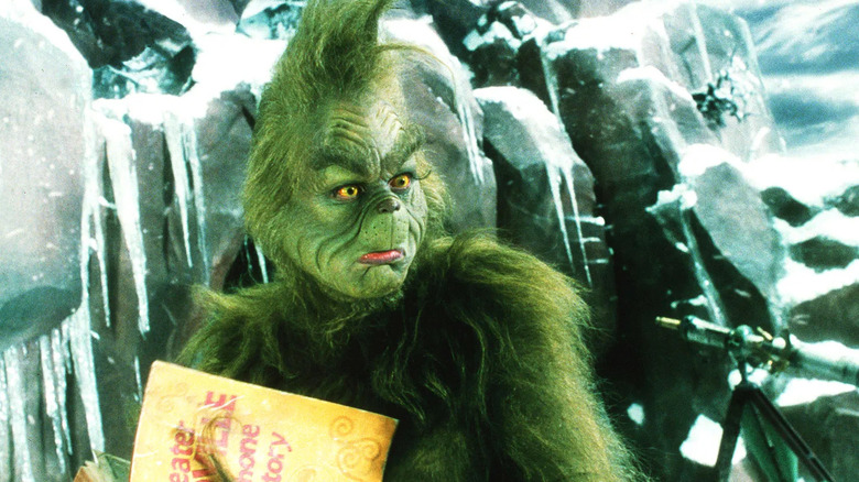 The Grinch in front of his mountain holding a telephone book