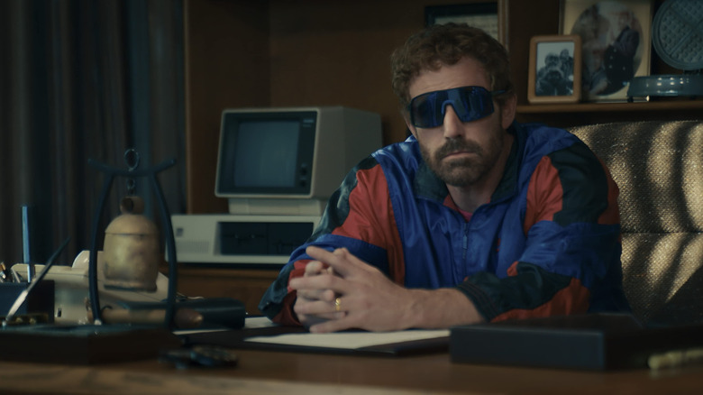 Phil Knight wearing sunglasses and sitting at his desk in Air
