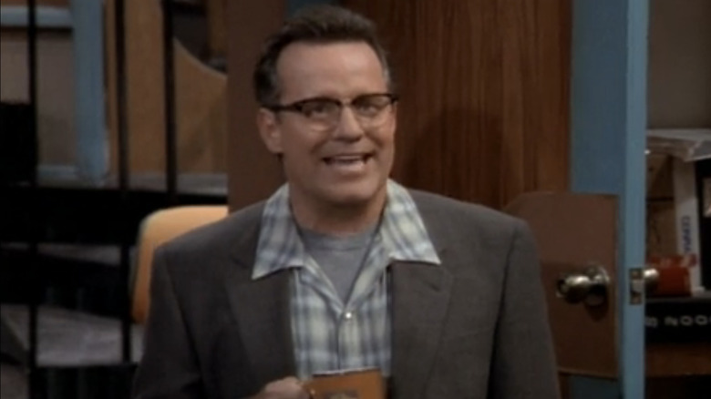 Phil Hartman stands on his knees on "NewsRadio"