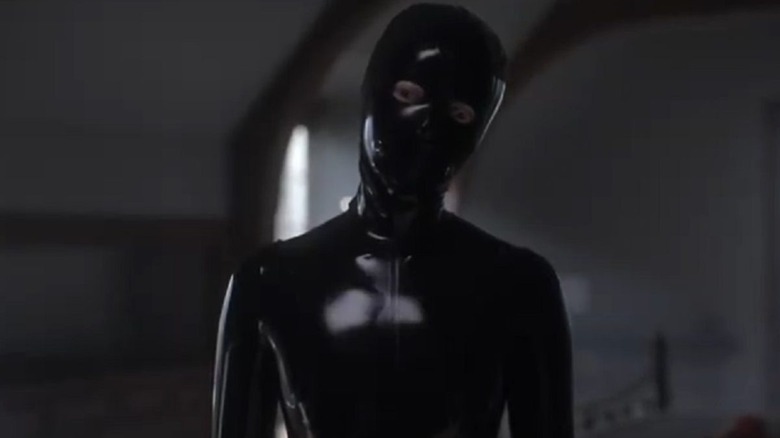 A person in a black vinyl gimp suit tilts their head in "American Horror Story" (2011-present)